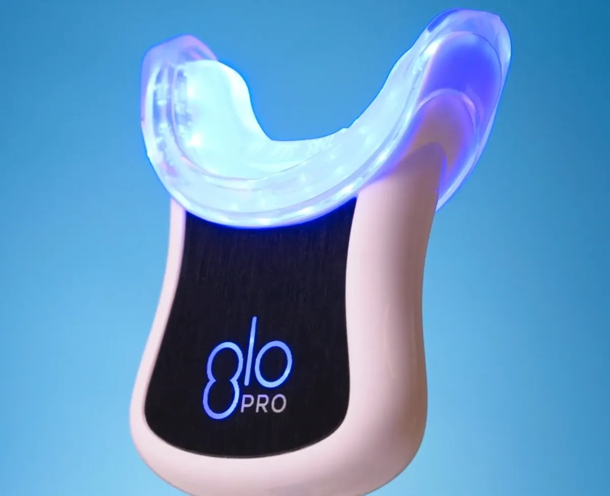 The GLO wearable LED whitening mouthpiece connected to its handheld device
