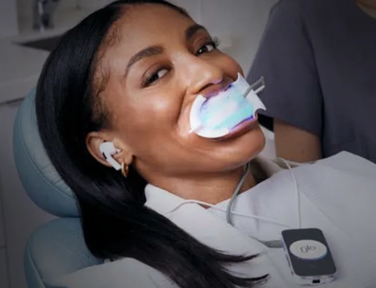 Patient reclined in the dental chair wearing the GLO LED whitening mouthpiece