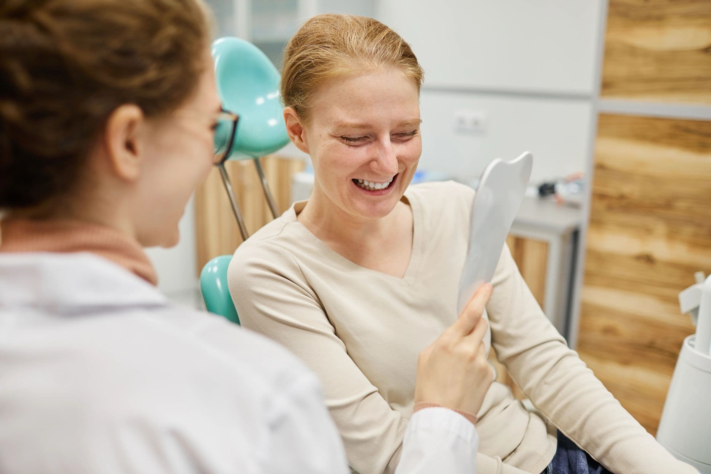 A patient at Miller Dental Care in Orillia admires her new smile in a hand mirror.
