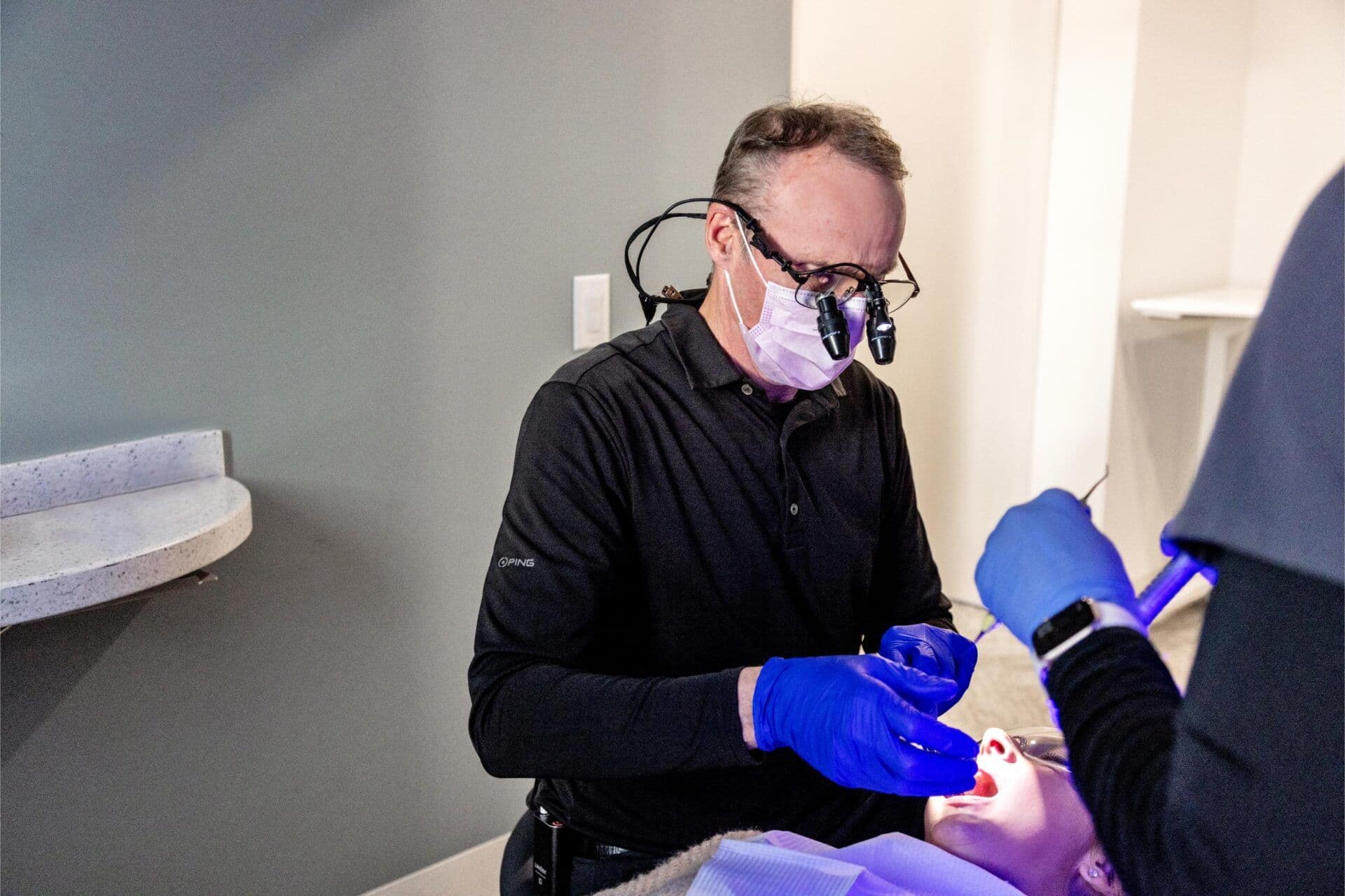 Dentist and dental assistant working together during a dental procedure, using professional tools and magnifying loupes at Miller Dental Care.